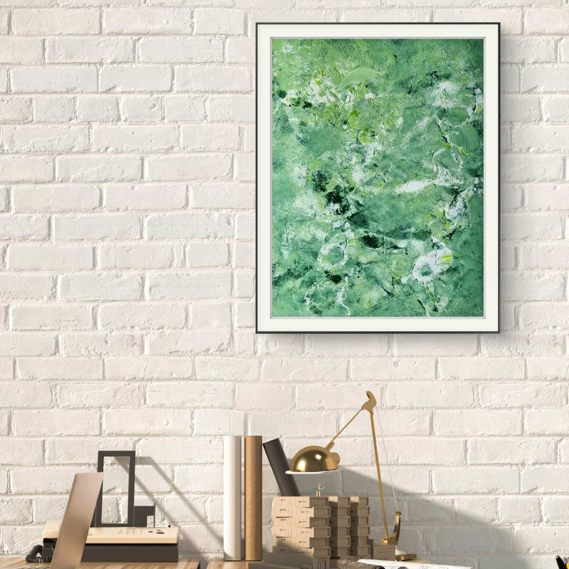 Green and white abstract painting in a black frame on a white brick wall in an office created by up-and-coming artist Jeanette Haga as decor for modern homes