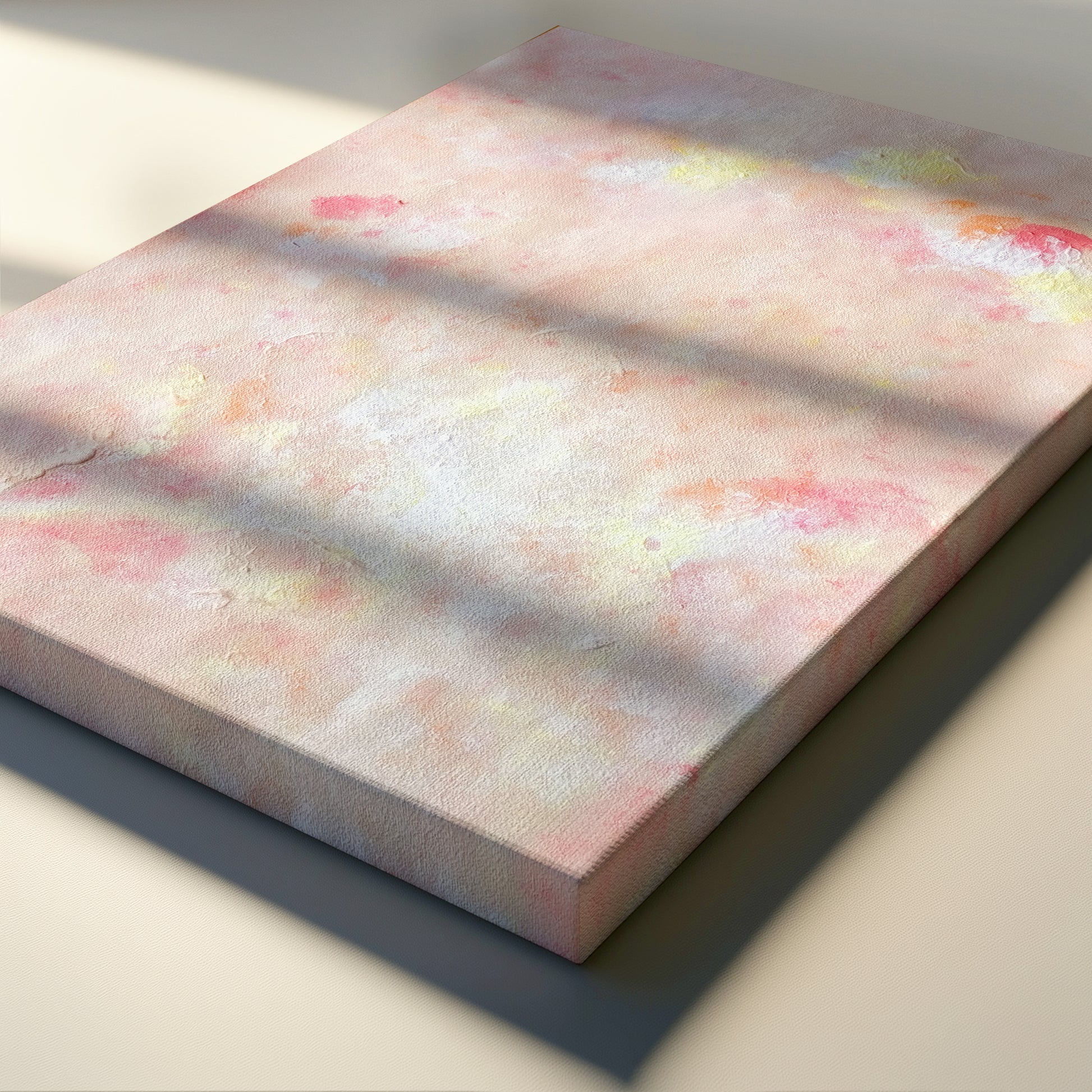 A square canvas print with an abstract pastel design featuring pink, white, and soft yellow tones, styled with diagonal window-light shadows across its surface.