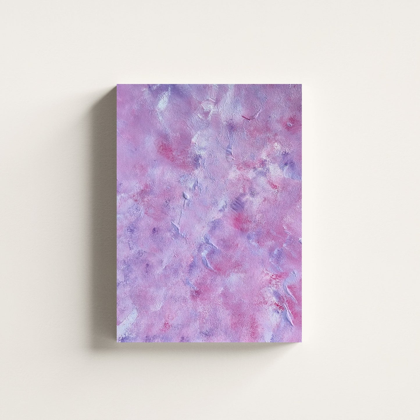 A vertical canvas wall art print featuring a textured, marbled abstract pattern in shades of lavender, purple, and pink, displayed against a clean off-white wall.