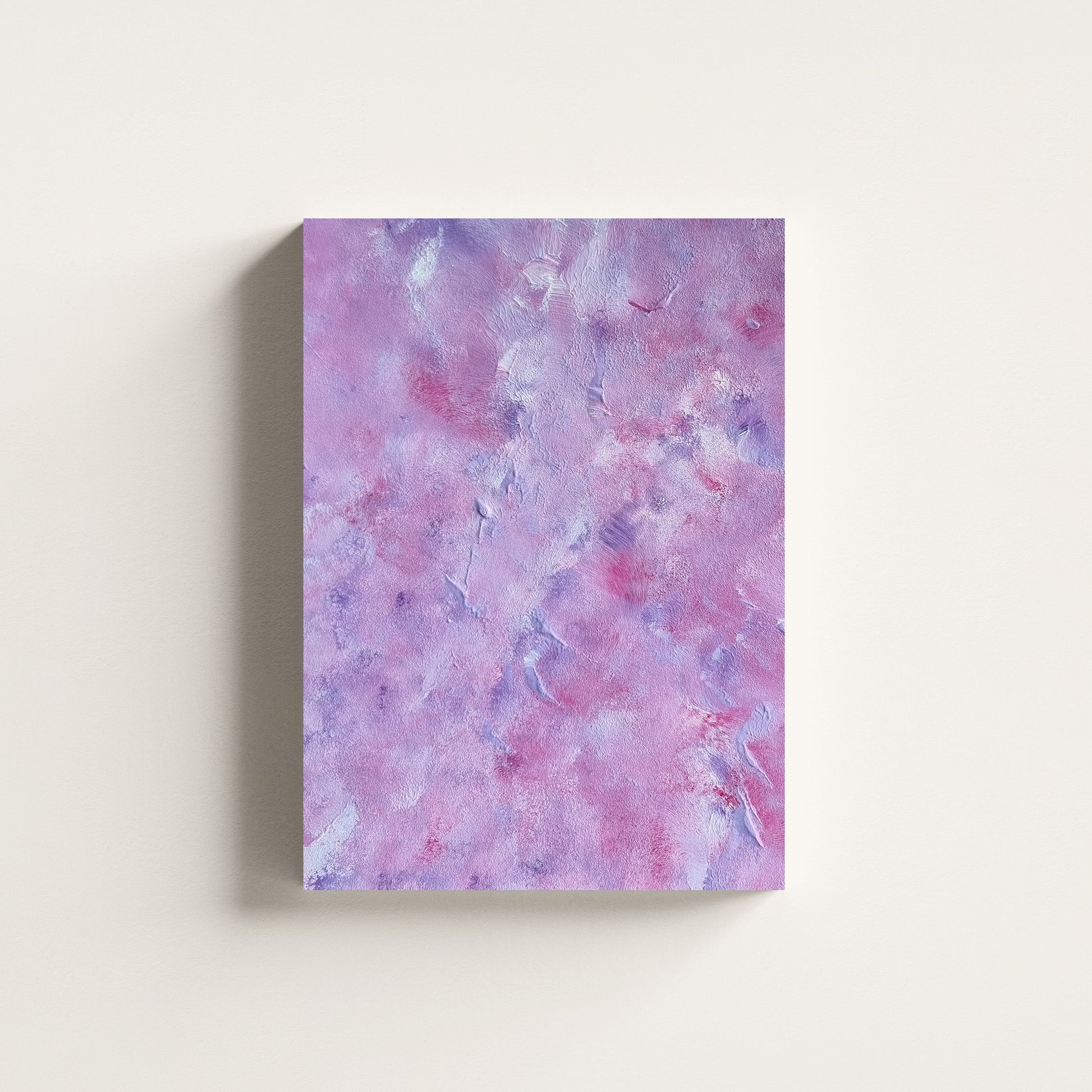 A vertical canvas wall art print featuring a textured, marbled abstract pattern in shades of lavender, purple, and pink, displayed against a clean off-white wall.