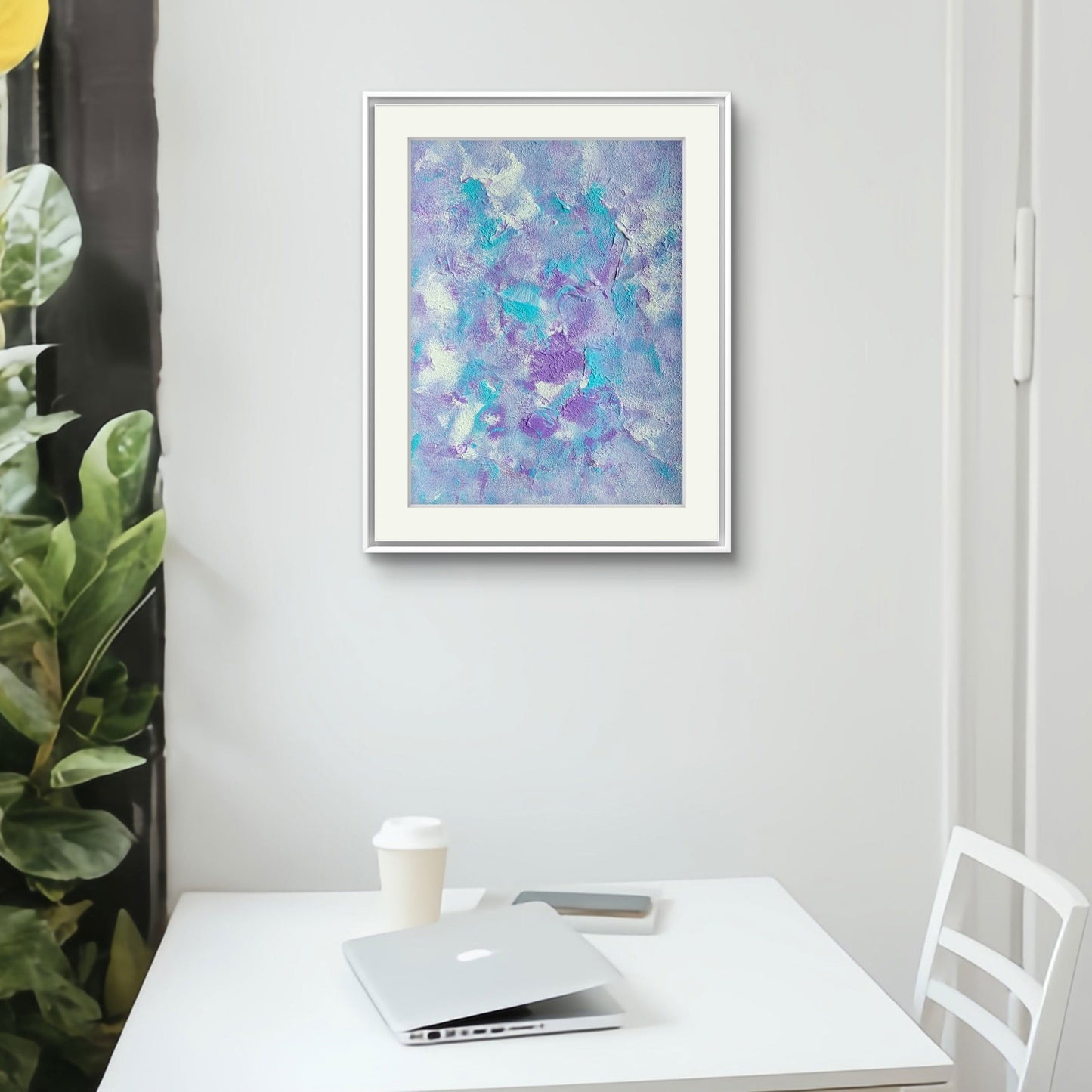 Original one of a kind colorful abstract acrylic art piece in pastel purple, blue and white, hanging vertically against a white white wall as decor in a modern white home office with a white table, a white chair, a macbook and a take away coffee cup 