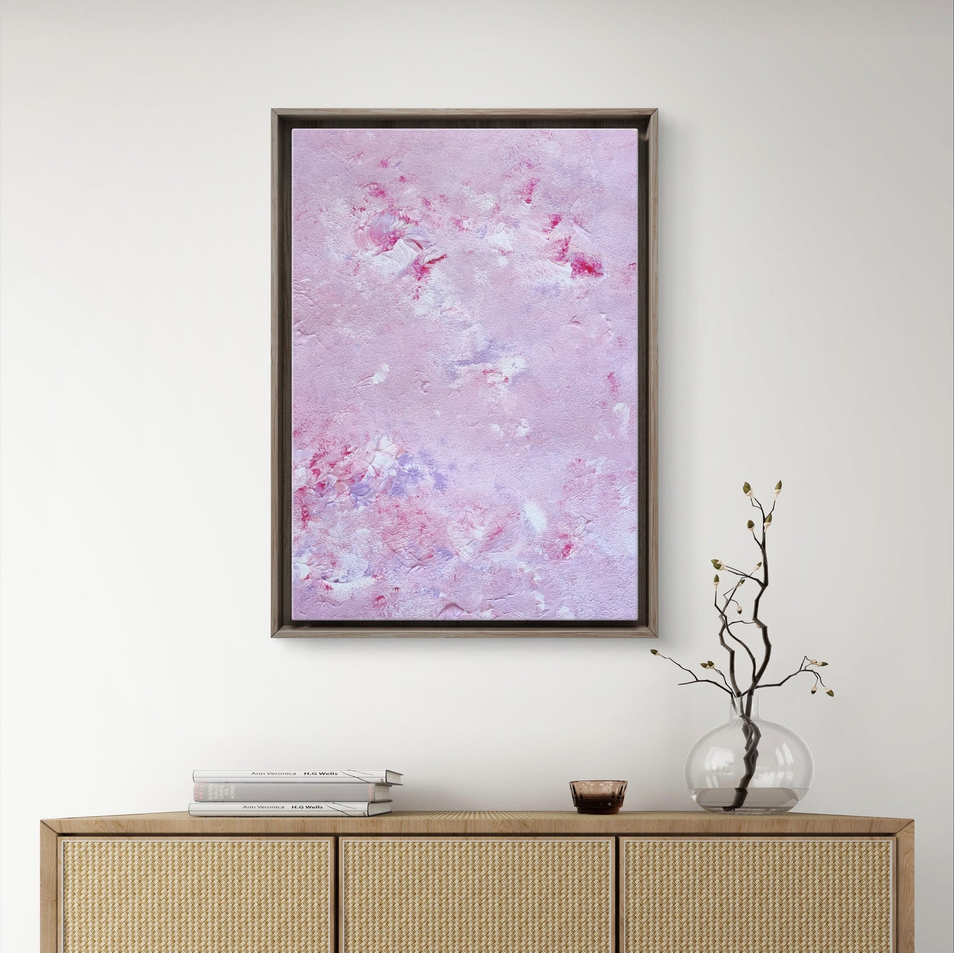 Original one of a kind colorful abstract acrylic art piece in pink, lilac and red, hanging vertically against a white wall as decor over modern light wood furniture