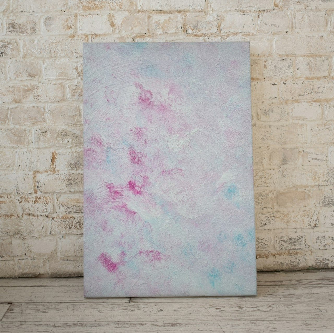 Pastel blue, Feel good one-of-a-kind colorful abstract art poster created from an original painting by up-and-coming scandinavian artist Jeanette Haga as decor in a modern home leaning vertically on a beige brick wall