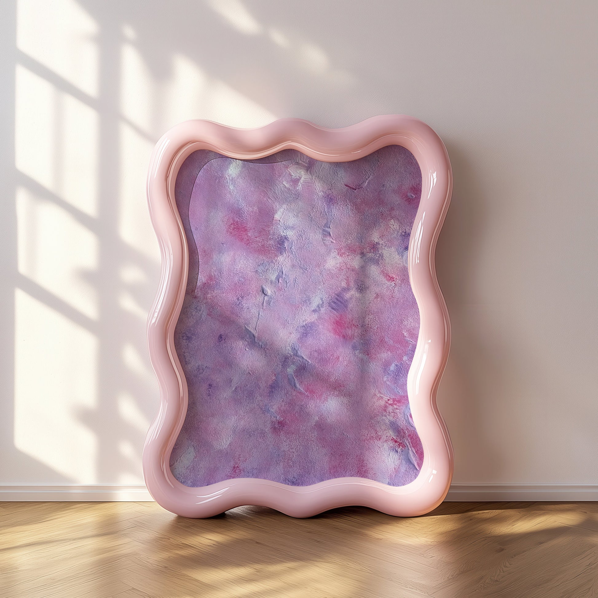 A wavy-edged mirror with a glossy light pink frame leans against a beige wall on a light wood floor, with soft window shadow patterns cast across the scene.