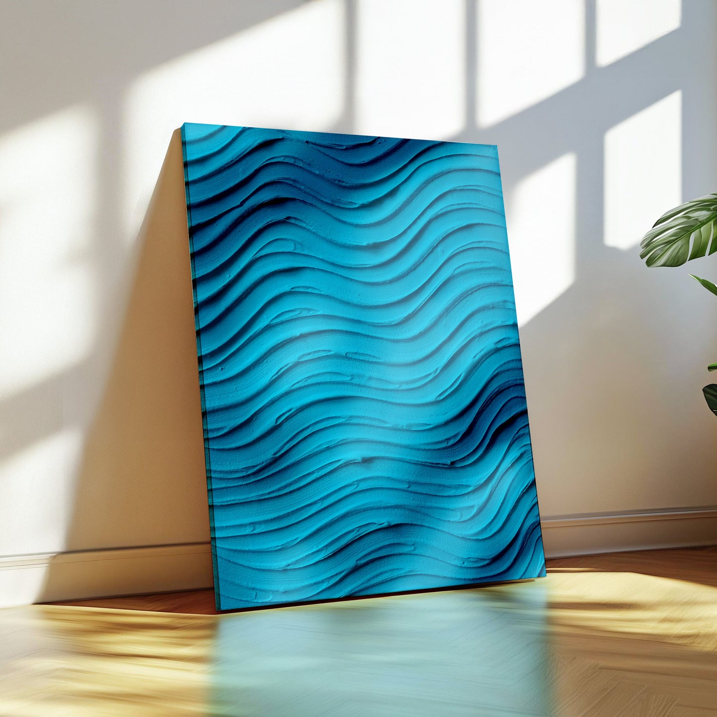 A vertical canvas wall art print with a 3D wavy texture in shades of blue, leaning against a beige wall on a wooden floor next to a potted green plant.