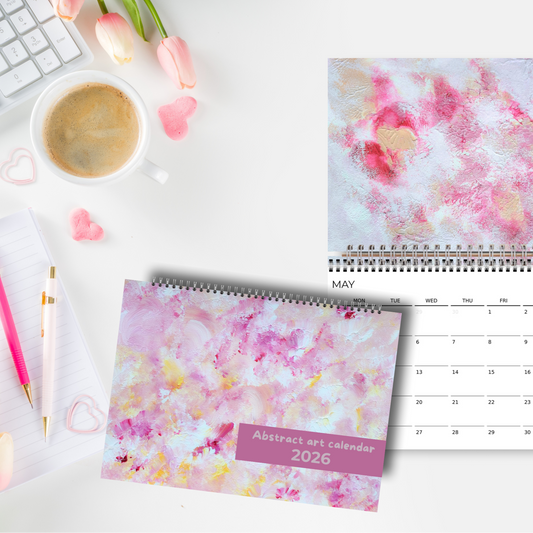 horizontal purple abstract art calendar by scandinavian artist laying on a white minimalistic desk with flowers, pens and a keyboard, creating a contrast and feminine effect to the home office. 
