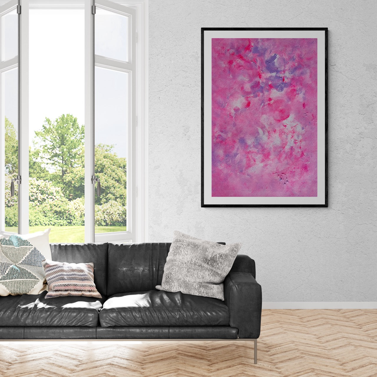 Pink, purple and white abstract art poster with a black frame hanging vertically on a grey sement wall in a stately house with a view to a green park outside. In front of the painting is a black leather sofa with cushions. The floor is wood and herringbone pattern 