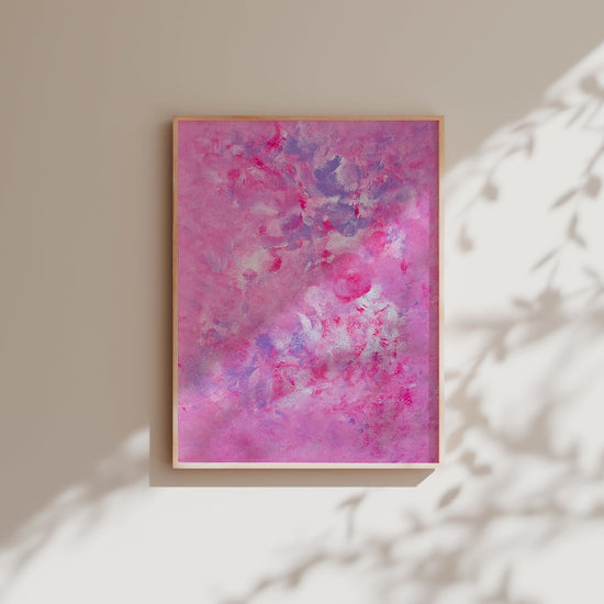 pink art poster hanging on a white wall with daylight